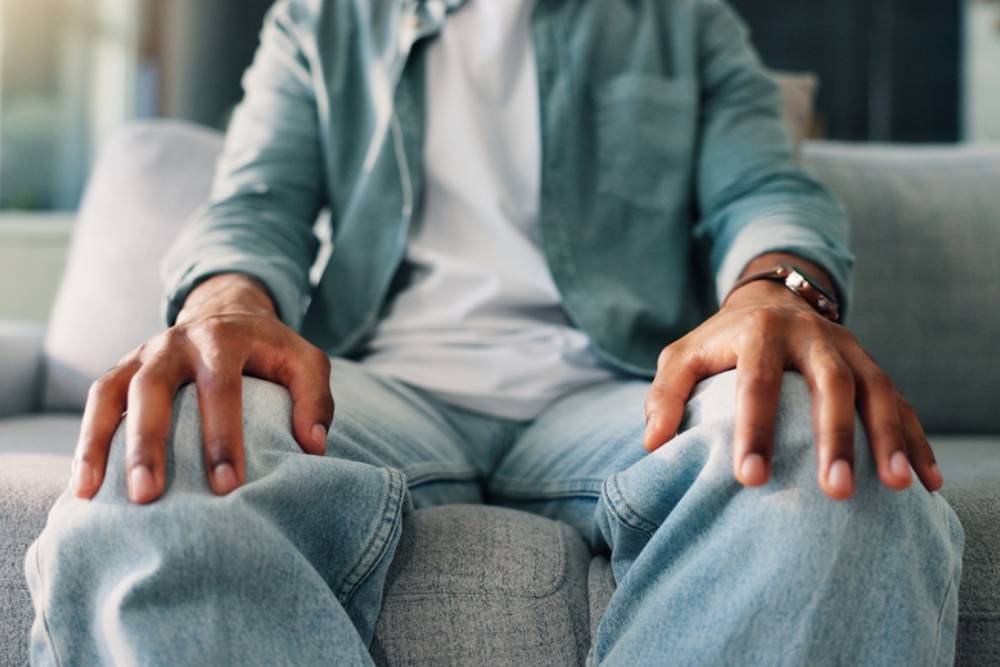Anxiety, hands and therapy with person on sofa in ptsd or trauma counseling session closeup